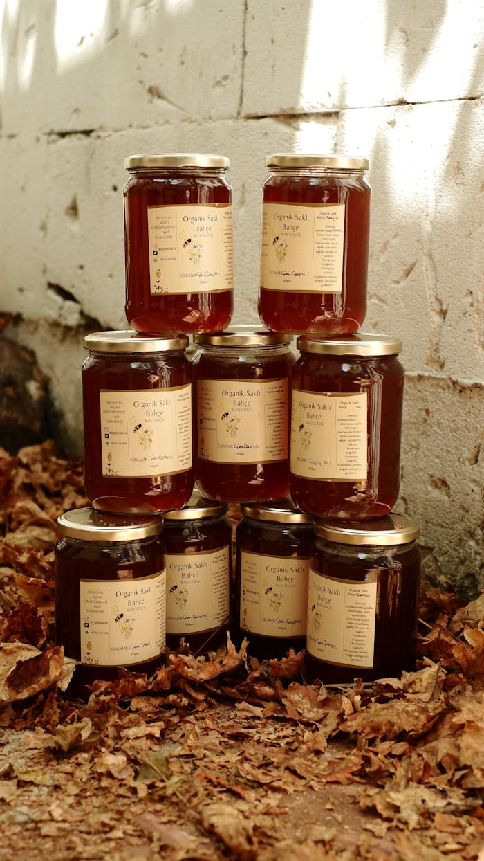 Elegant composition of organic honey jars on autumn leaves, perfect for food and nature themes.