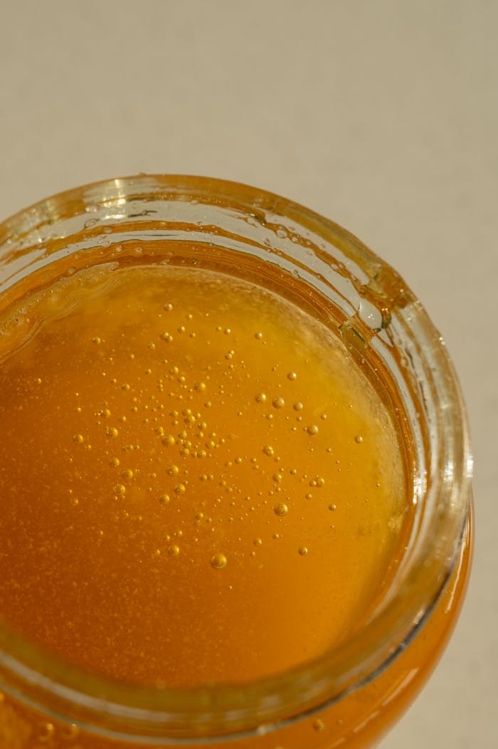 Close-up of golden honey in a jar showcasing its rich amber hue and sticky texture.